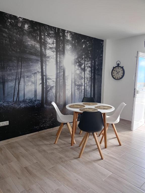 a table and chairs in a room with a forest mural at La Lunita in Valverde