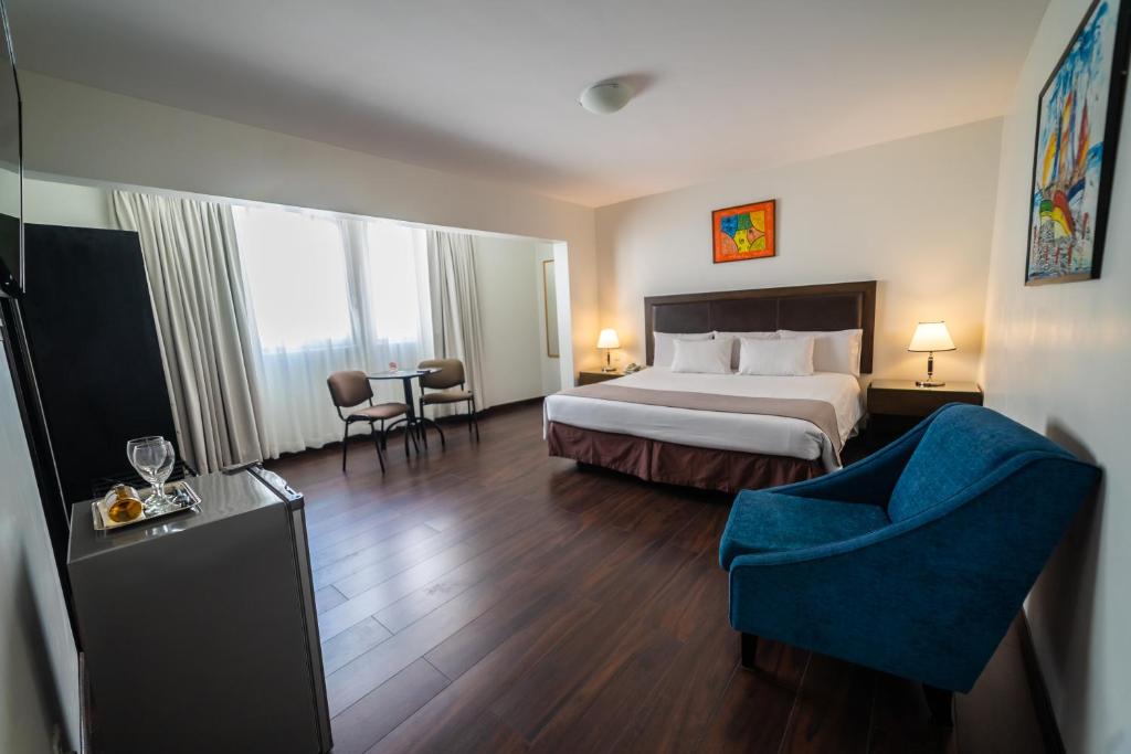 a hotel room with a bed and a blue chair at Hotel Calacoto in La Paz