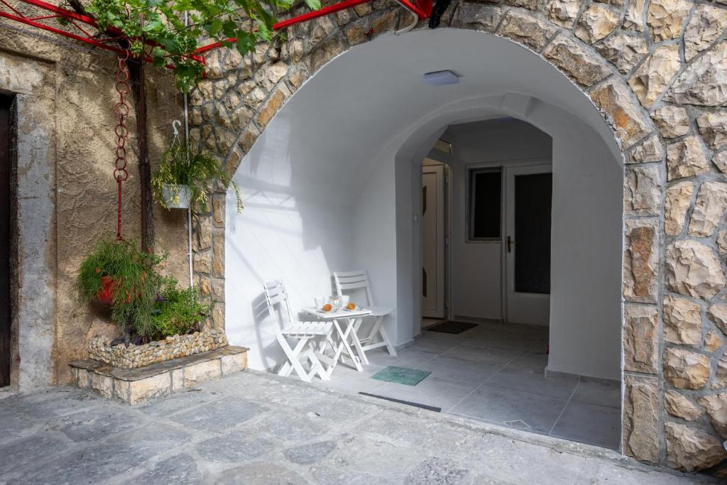 um arco num edifício de pedra com uma mesa e cadeiras em Apartment GAVIOTA Krk em Krk