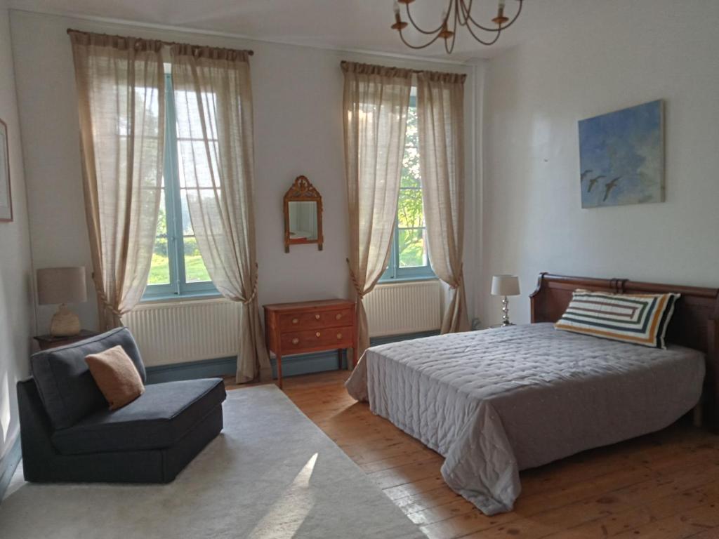 um quarto com uma cama, uma cadeira e janelas em 1812 Route de Baziège à Labège em Labège