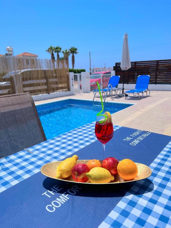 a plate of fruit on a table with a drink at 3 Bedroom Coral Bay Beach Seaview Villa II Private Pool in Coral Bay