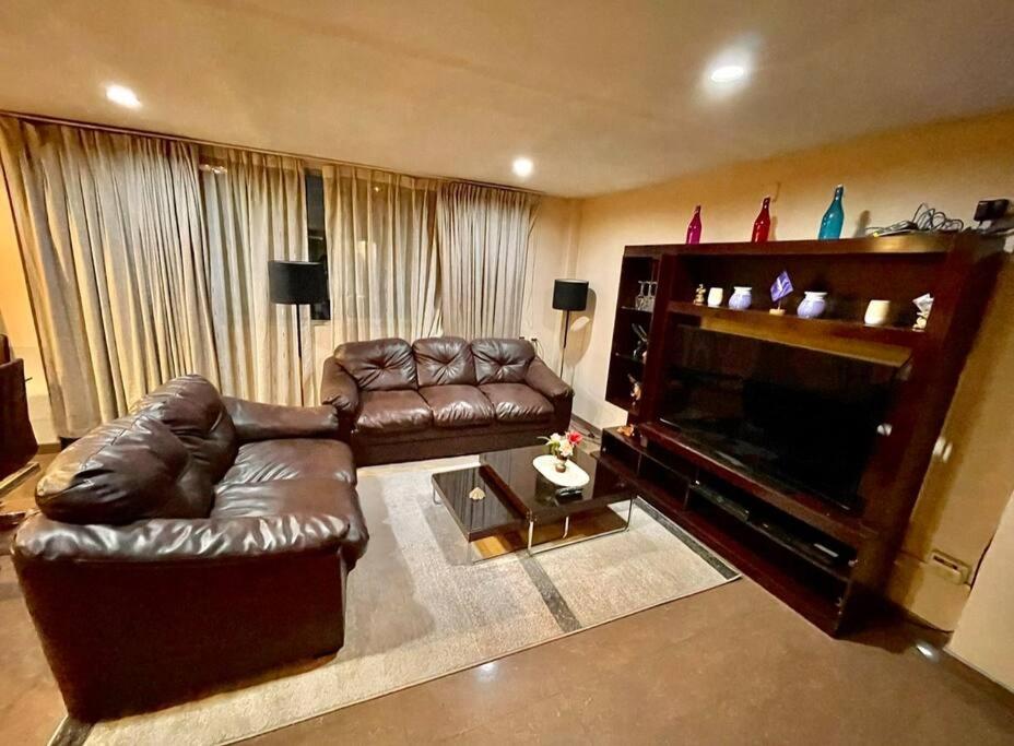 uma sala de estar com um sofá de couro e uma lareira em Apartment em Cusco