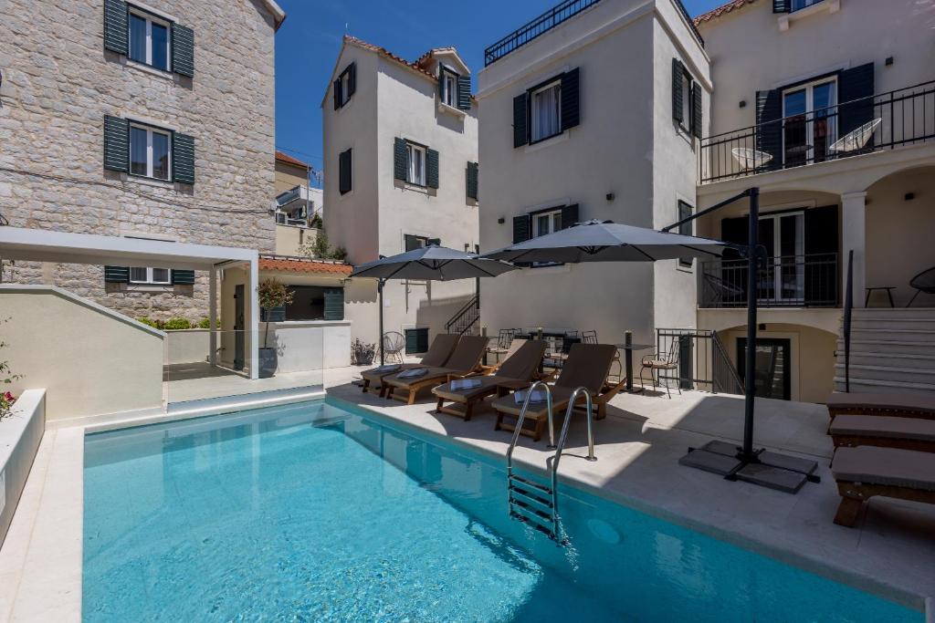 einen Pool mit Stühlen und Sonnenschirmen neben einem Gebäude in der Unterkunft Sperone Hotel in Split