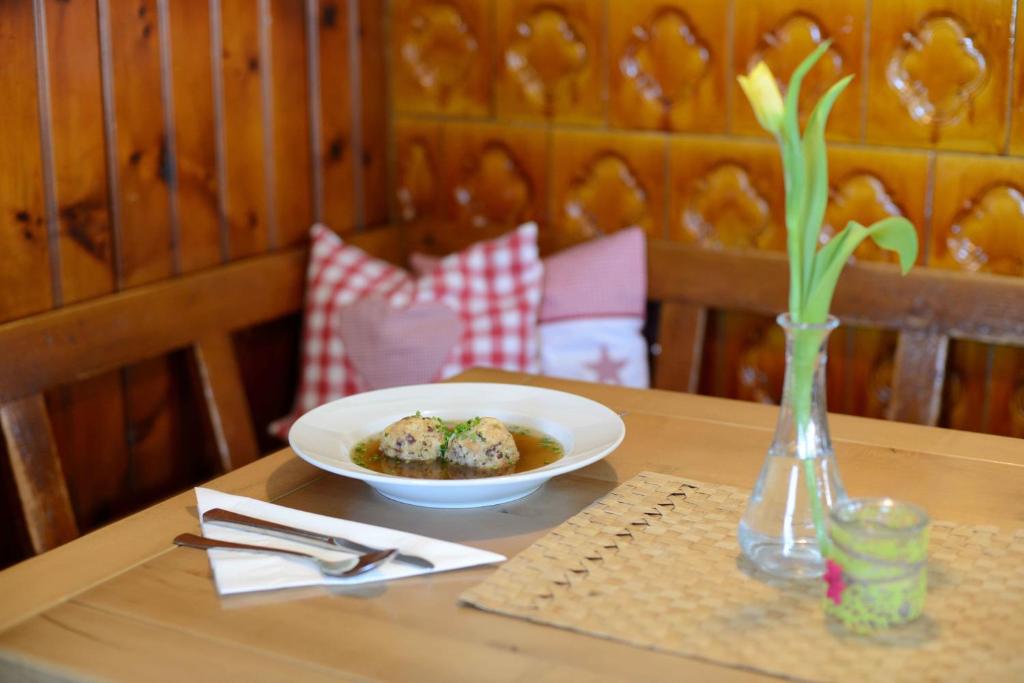 a table with a bowl of food and a vase at Alpengasthof zur Post in Schattwald