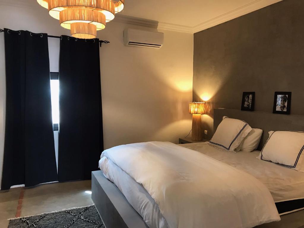 een slaapkamer met een wit bed en een kroonluchter bij VILLA PISCINE MARRAKECH in Marrakesh