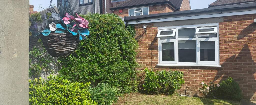 a brick house with a bush with flowers on it at Garden Room in Northolt