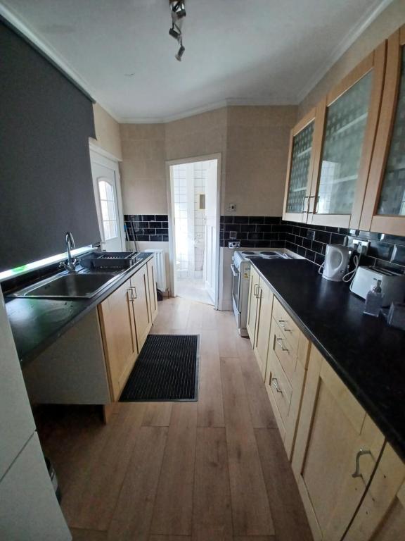 een grote keuken met houten vloeren en zwarte aanrechtbladen bij Newcastle Home in Saint Peters
