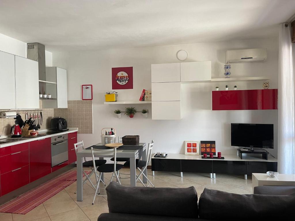 uma cozinha com armários vermelhos e brancos e uma mesa em FIERA MILANO-RHO APARTMENT em Pero