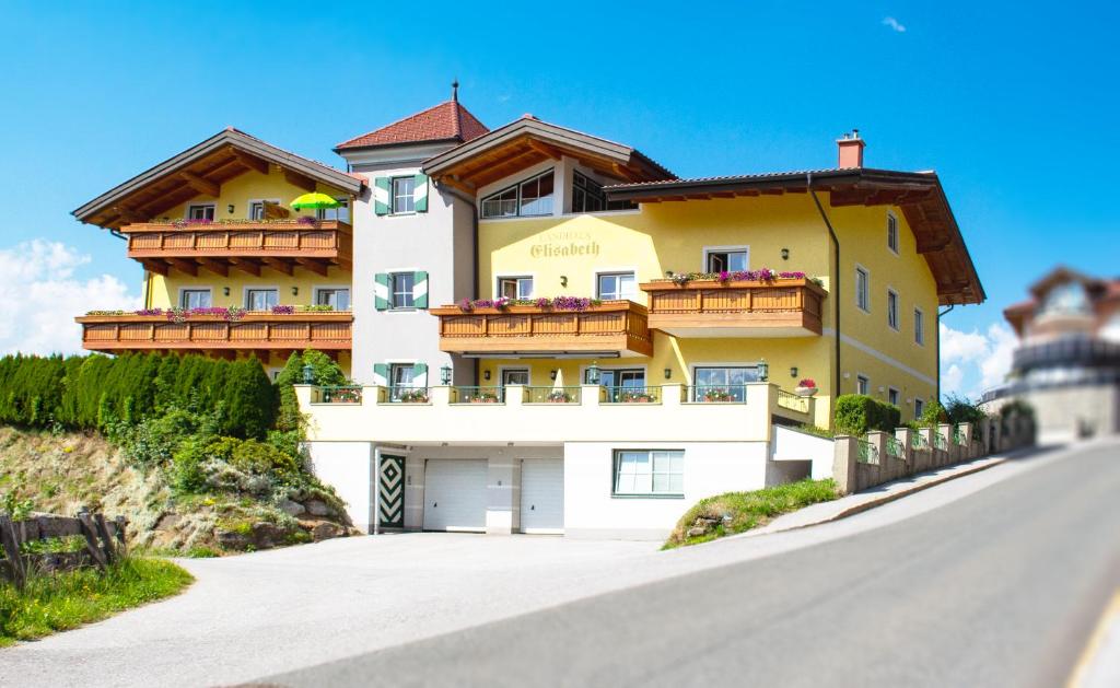 a large yellow building with wooden balconies on a road at Landhaus Elisabeth in Sankt Johann im Pongau