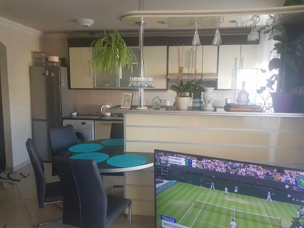 a kitchen with a table with a tennis game on a computer monitor at Elaktra Apartman in Szolnok