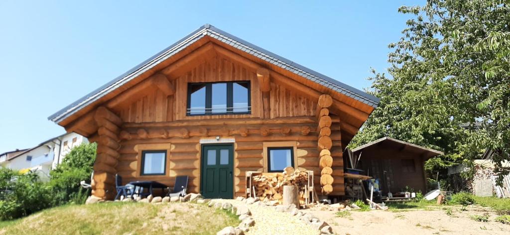 una casa di tronchi con una porta verde su una collina di Holzhaus Wildsbergblick 