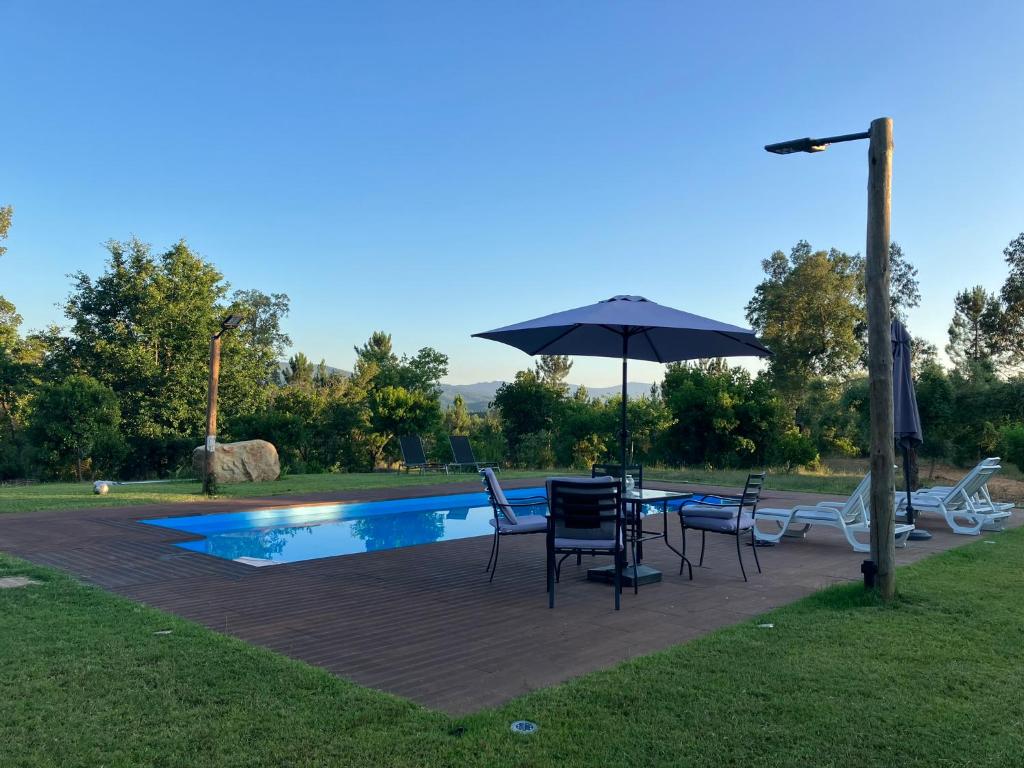 科英布拉的住宿－Quinta da Meda，游泳池旁配有遮阳伞的桌椅