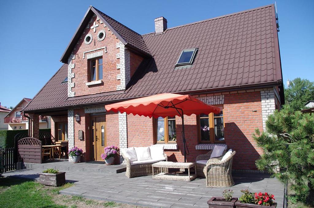 uma casa de tijolos com um pátio com um guarda-chuva vermelho em Pańska Izba em Chałupy