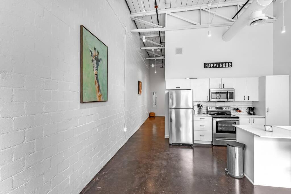 cocina con paredes blancas y nevera de acero inoxidable en Deep Ellum Art Novea en Dallas