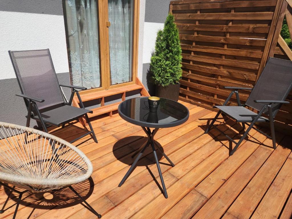a patio with a table and chairs on a deck at Bursztynowe Wczasy Sasino in Sasino