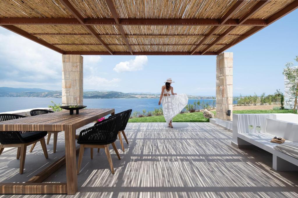 a woman walking on the deck of a house with a table and chairs at Sun rise Villas ammouliani in Ammouliani