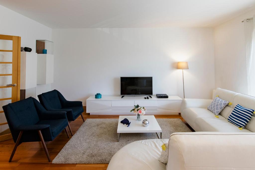 uma sala de estar com um sofá branco e duas cadeiras azuis em Garden Mills Apartment em Lisboa