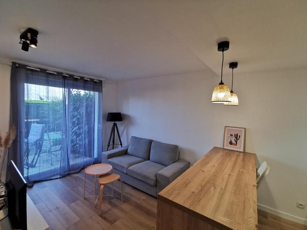 ein Wohnzimmer mit einem Sofa und einem Tisch in der Unterkunft Appartement proche plages in Brancieux