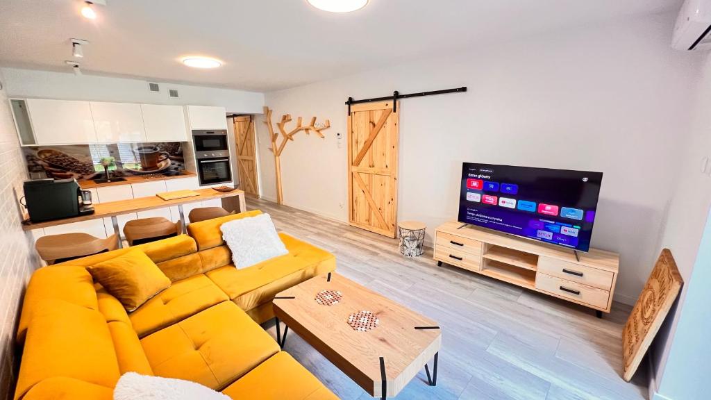 salon z żółtą kanapą i telewizorem z płaskim ekranem w obiekcie CHARZYKOWSKIE TARASY w Charzykowach
