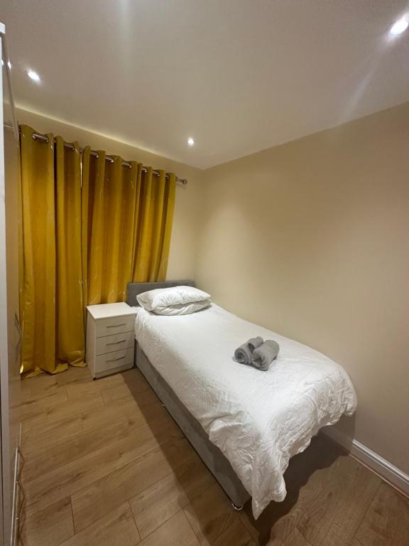 um quarto com uma cama e uma cortina amarela em 2BR Flat near Central Southall em Southall