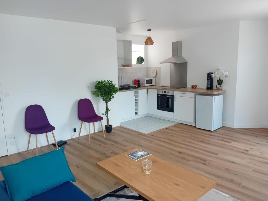 une cuisine avec deux chaises violettes et une table dans une pièce dans l'établissement L'EDEN DE CHARTRES, à Chartres