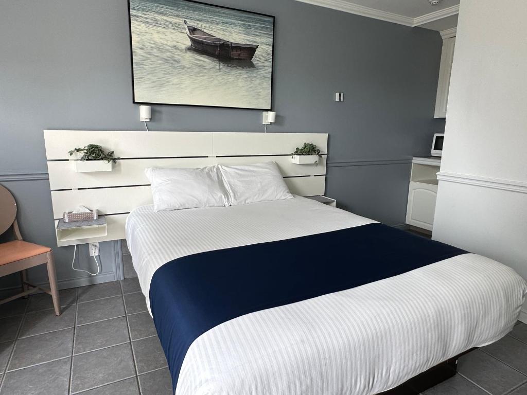 a bedroom with a bed and a desk with a boat on the wall at Motel Le Refuge in Sherbrooke