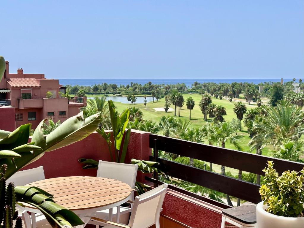 balcón con mesa, sillas y vistas a un campo en Playa Granada Golf Apartamentos, en Motril