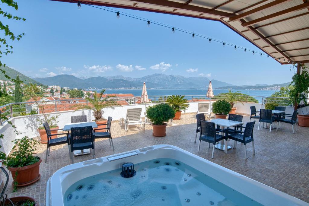 a hot tub on a patio with tables and chairs at Garni Hotel Milica in Herceg-Novi