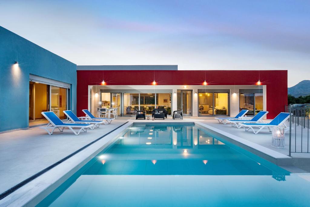 a swimming pool with blue chairs and a house at Gramvousa Villas in Kissamos