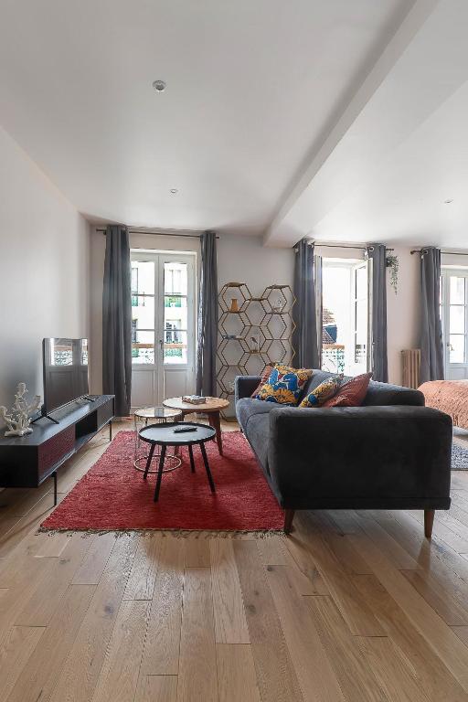 a living room with a black couch and a red rug at Residence Aristide Briand - Appartements design centre ville in Vichy