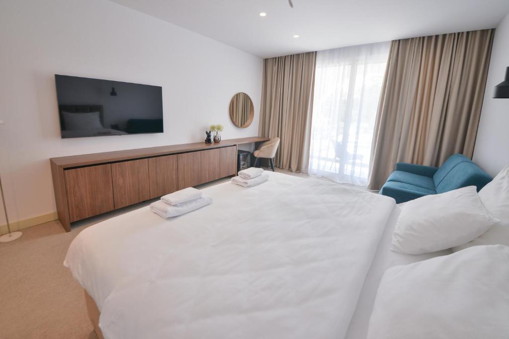 a hotel room with a large white bed and a television at Luxury Hotel Riva - Budva in Budva