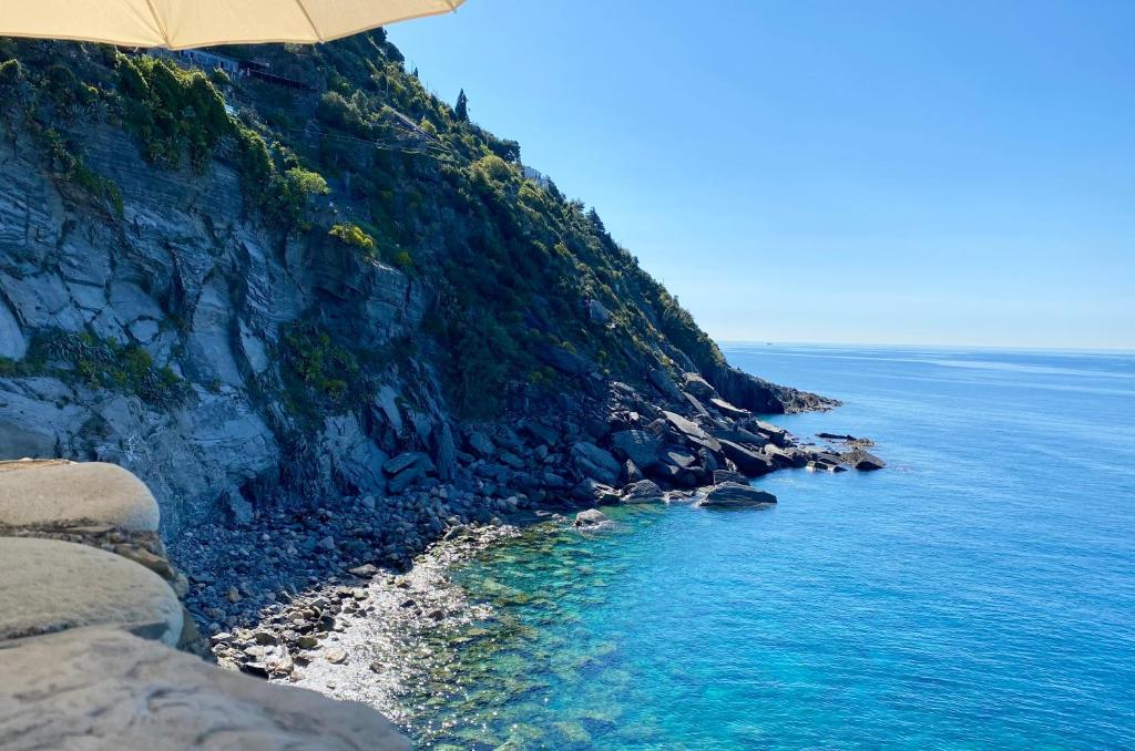 a beach with an umbrella next to the ocean at La Marina Tower Apartment with private sea view terrace in Vernazza