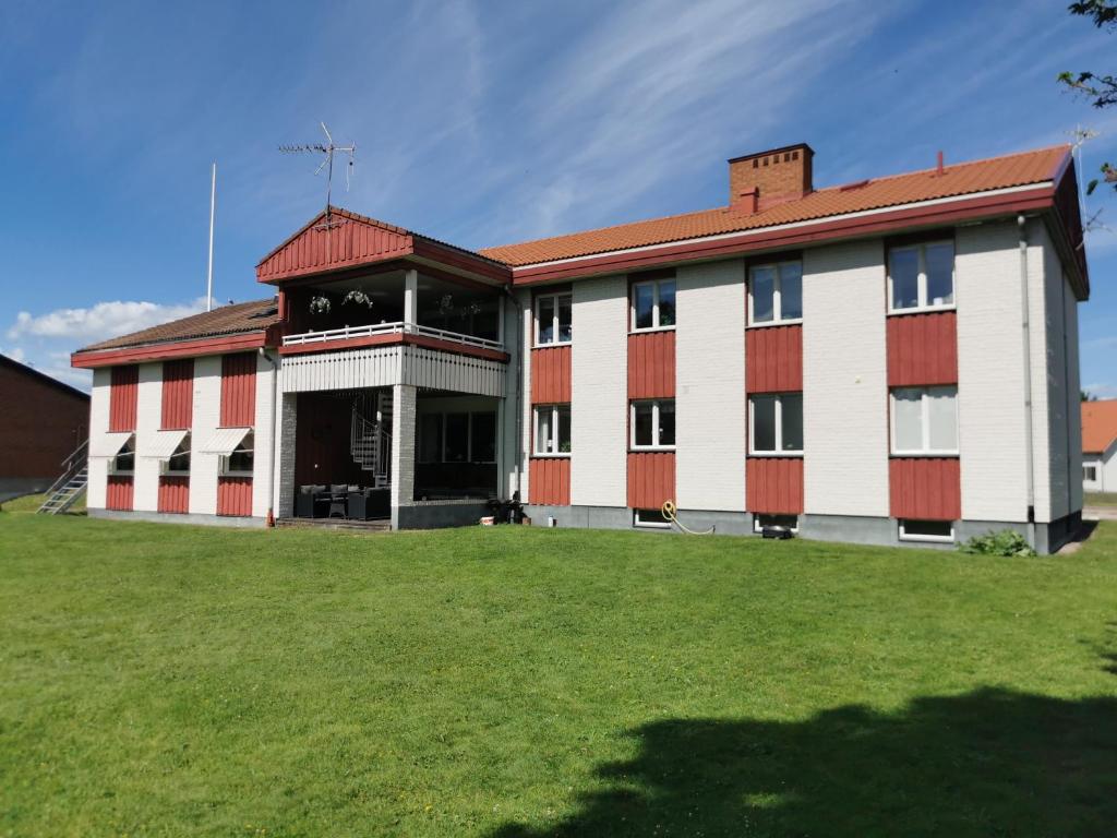 a red and white building with a grass yard at Saxvikens vandrarhem in Mora