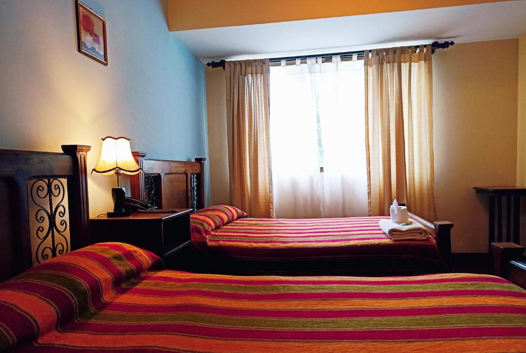 a hotel room with two beds and a window at Hotel Maison Fiori Prado in Cochabamba