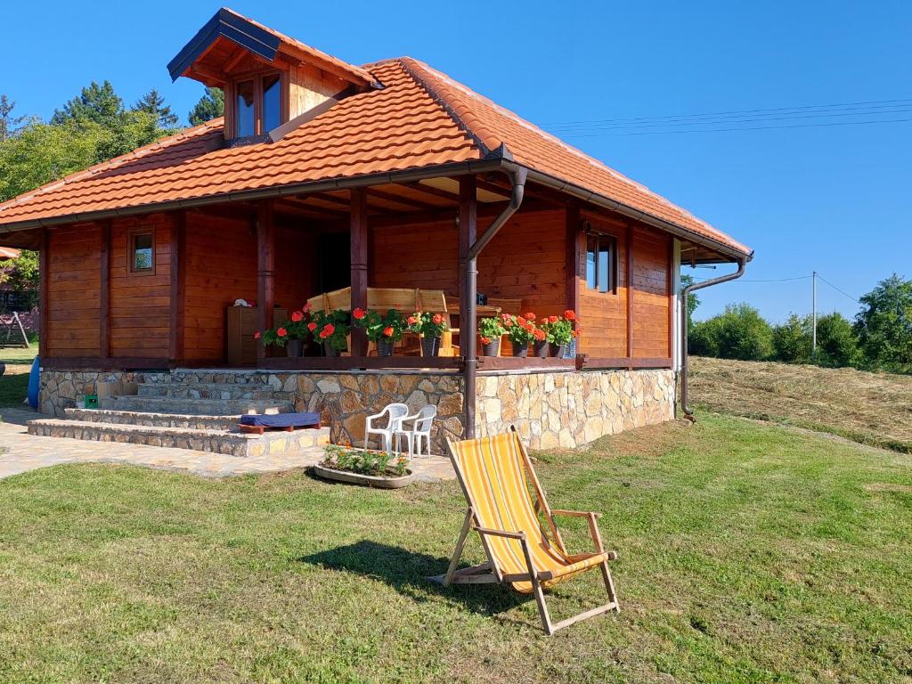 una casa de madera con una silla delante en Kuća za odmor Filipović en Gornji Milanovac