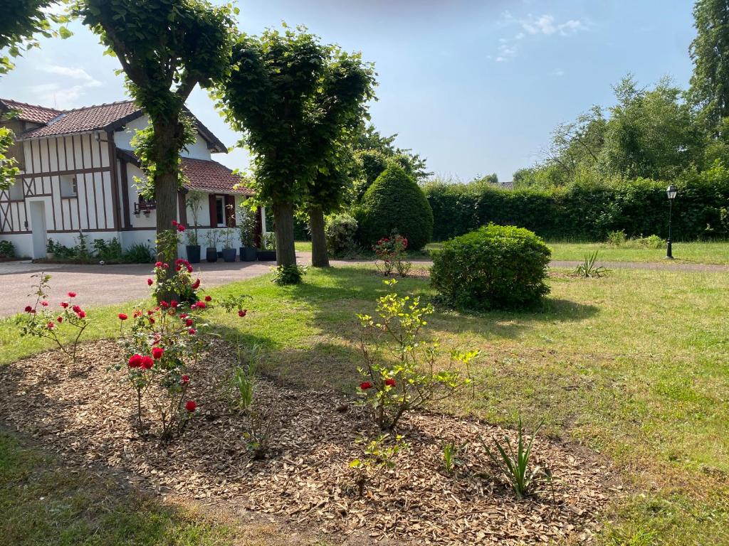un jardín con flores rojas frente a una casa en Gîte épicéa indépendant avec jardin, en Méry-sur-Oise