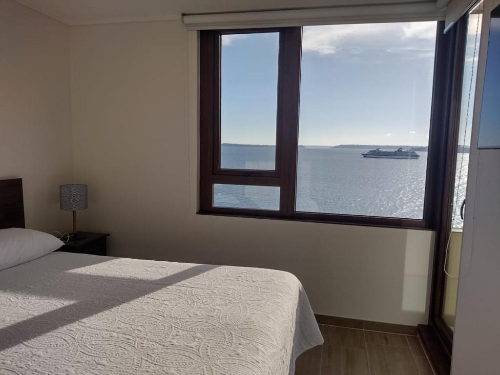 een slaapkamer met een groot raam met uitzicht op het water bij Departamentos Terramar in Puerto Montt