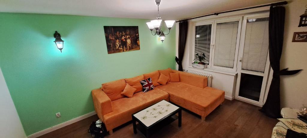 een woonkamer met een oranje bank en groene muren bij 2 Rooms Apartment in old Town in Košice