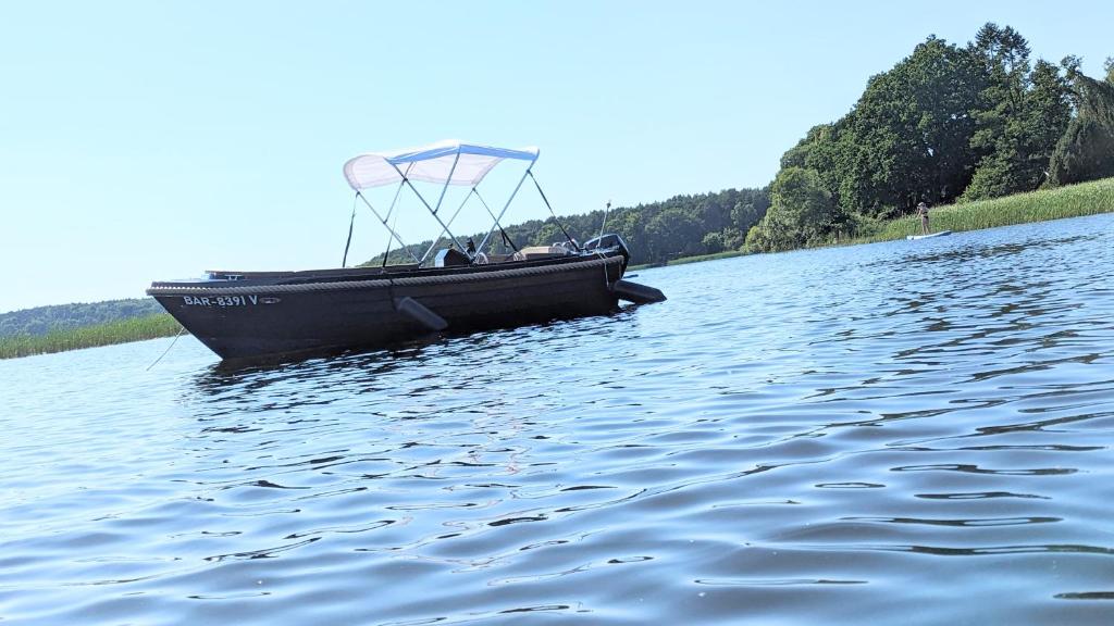 um barco preto sobre a água em um lago em Waterview - Schwimmendes Ferienhaus auf dem Wasser mit Blick zur Havel, inkl Motorboot zur Nutzung em Fürstenberg-Havel