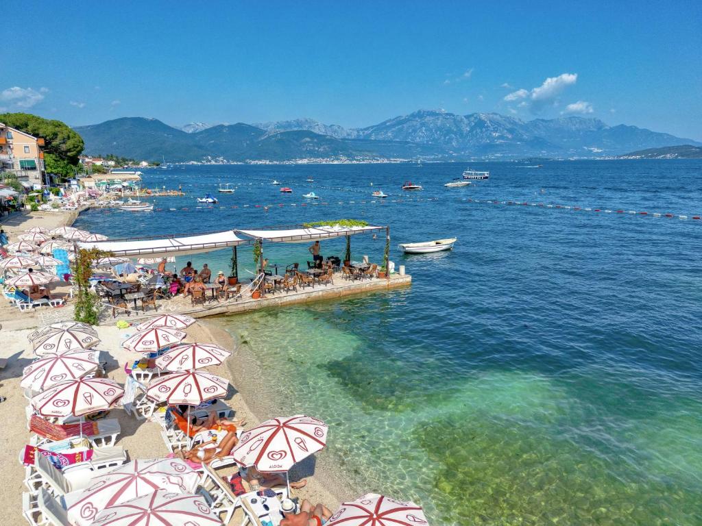 una spiaggia con ombrelloni e persone sedute sulla spiaggia di Garni Hotel Milica a Herceg-Novi