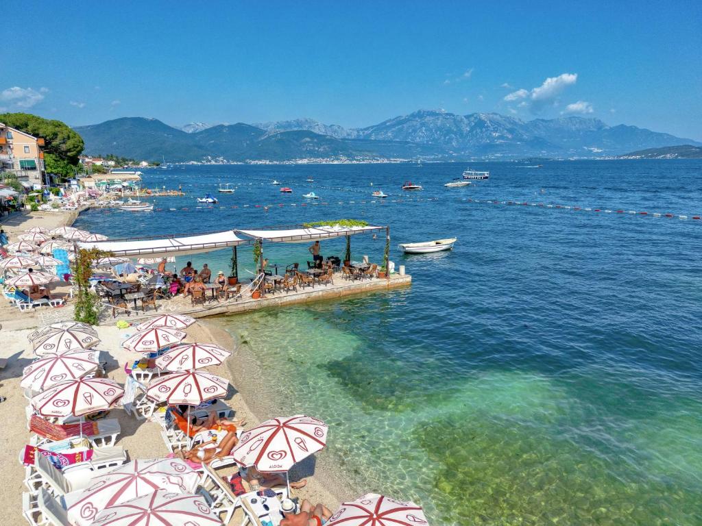 una playa con sombrillas y gente sentada en la playa en Garni Hotel Milica, en Herceg-Novi