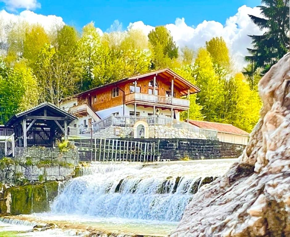 ein Haus neben einem Wasserfall neben einem Gebäude in der Unterkunft große Fewo in den Alpen zwischen See, Berg und Bach in Kiefersfelden