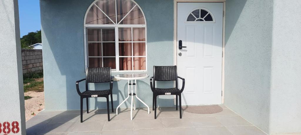 eine Terrasse mit 2 Stühlen und einem Tisch vor einer Tür in der Unterkunft Ocean view in Discovery Bay