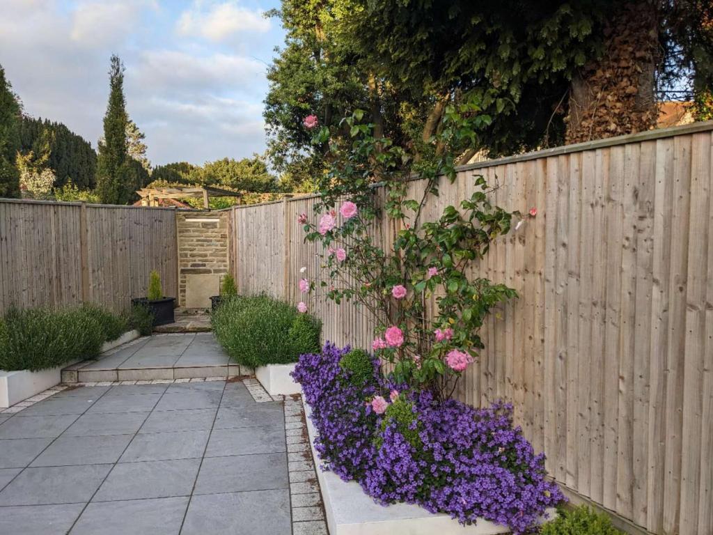 a fence with pink roses and purple flowers at 田园居 in Orpington