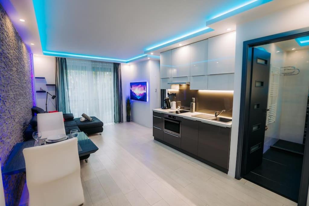 eine Küche mit einem Waschbecken und ein Wohnzimmer in der Unterkunft Luxury Smart Apartman JJ in Szeged