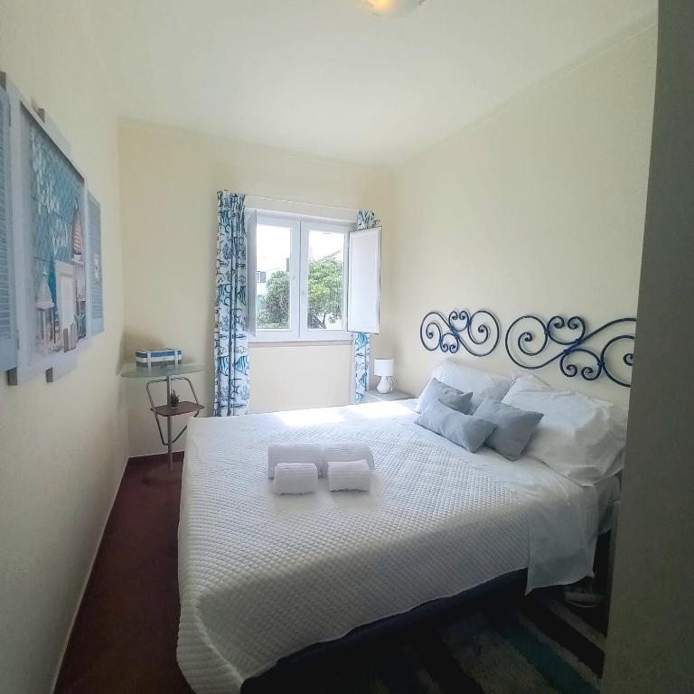 a bedroom with a white bed with two towels on it at Casa do Portão Azul - Tamboril in Atouguia da Baleia