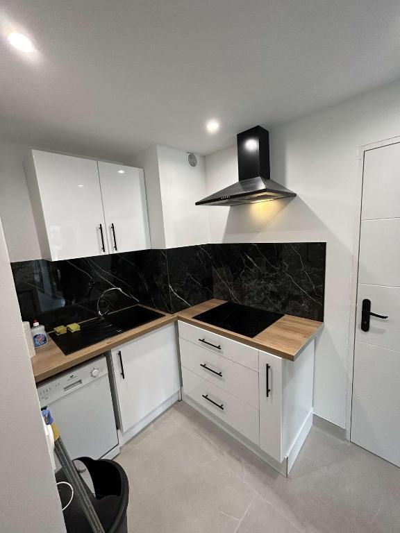 uma cozinha com armários brancos e um balcão preto em Appartement cap agde port 4 couchage em Cap d'Agde