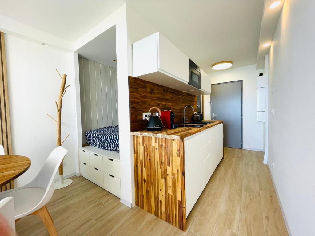 a kitchen with white cabinets and a table and a bed at Studio FRONT DE MER rénové in Le Barcarès