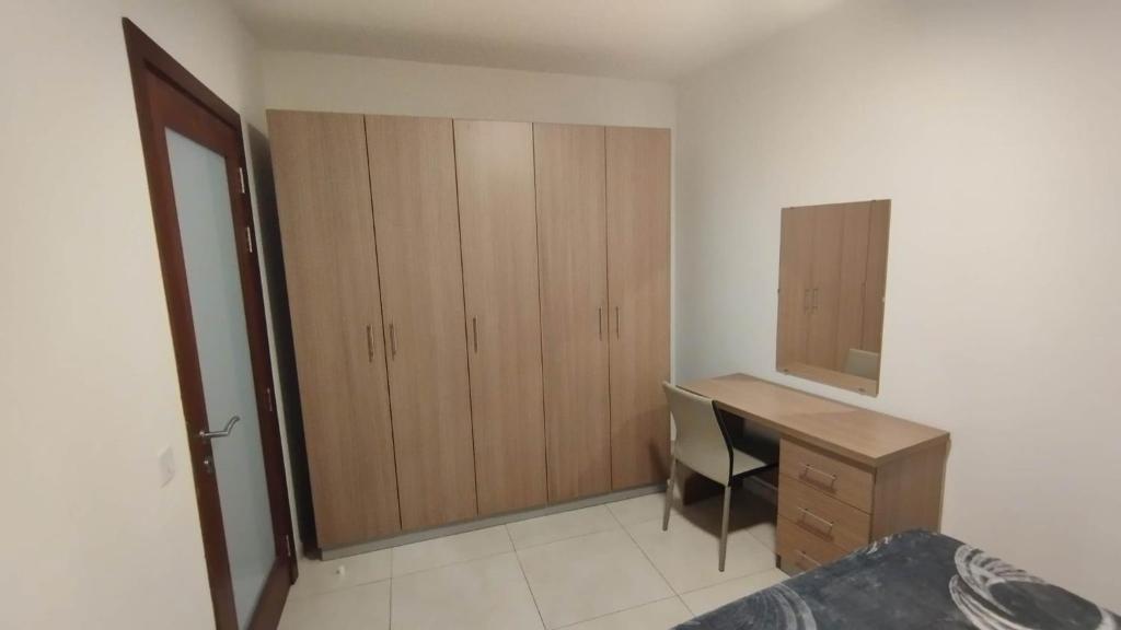 1 dormitorio con escritorio y armario de madera en Private Room in a Big aparment, en Msida