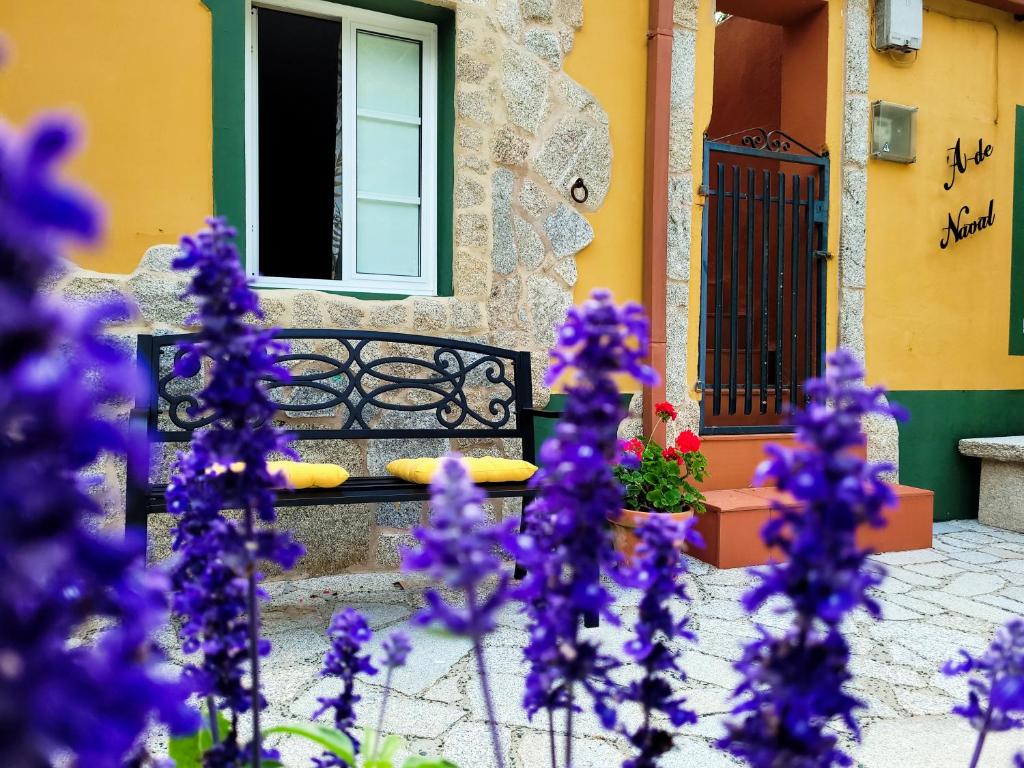 a bench in front of a house with purple flowers at La casita "A de Naval" in Pontevedra